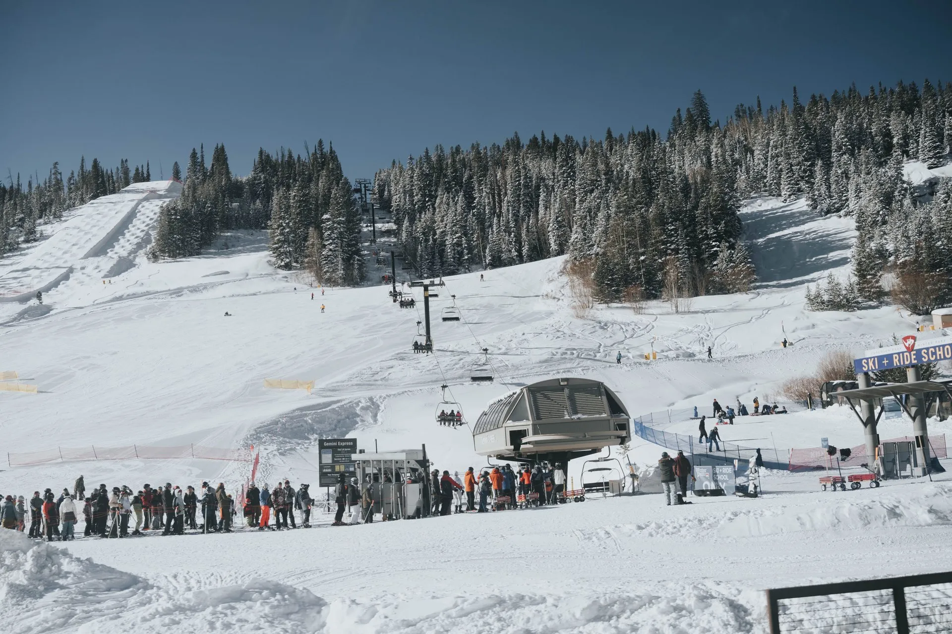 Skiers waiting in line at a chairlift base on Vail Mountain on a sunny winter day