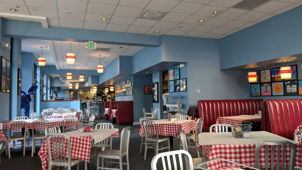 Pizzeria dining room with red-and-white checked tablecloths, red booths and blue walls