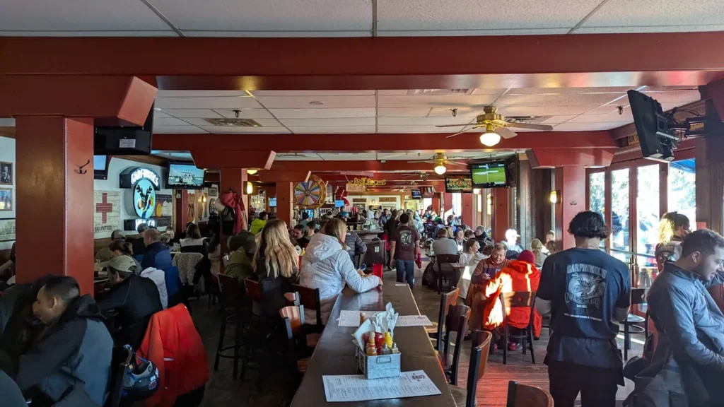 Busy dining room at Garfinkel's with wooden tables, TV screens and a red-painted ceiling